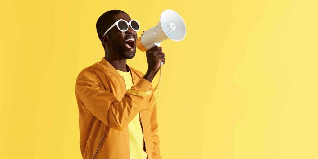 How to Promote Your Small Business Locally | 6 Simple Steps Graphic of a black man using a megaphone with a yellow background.
